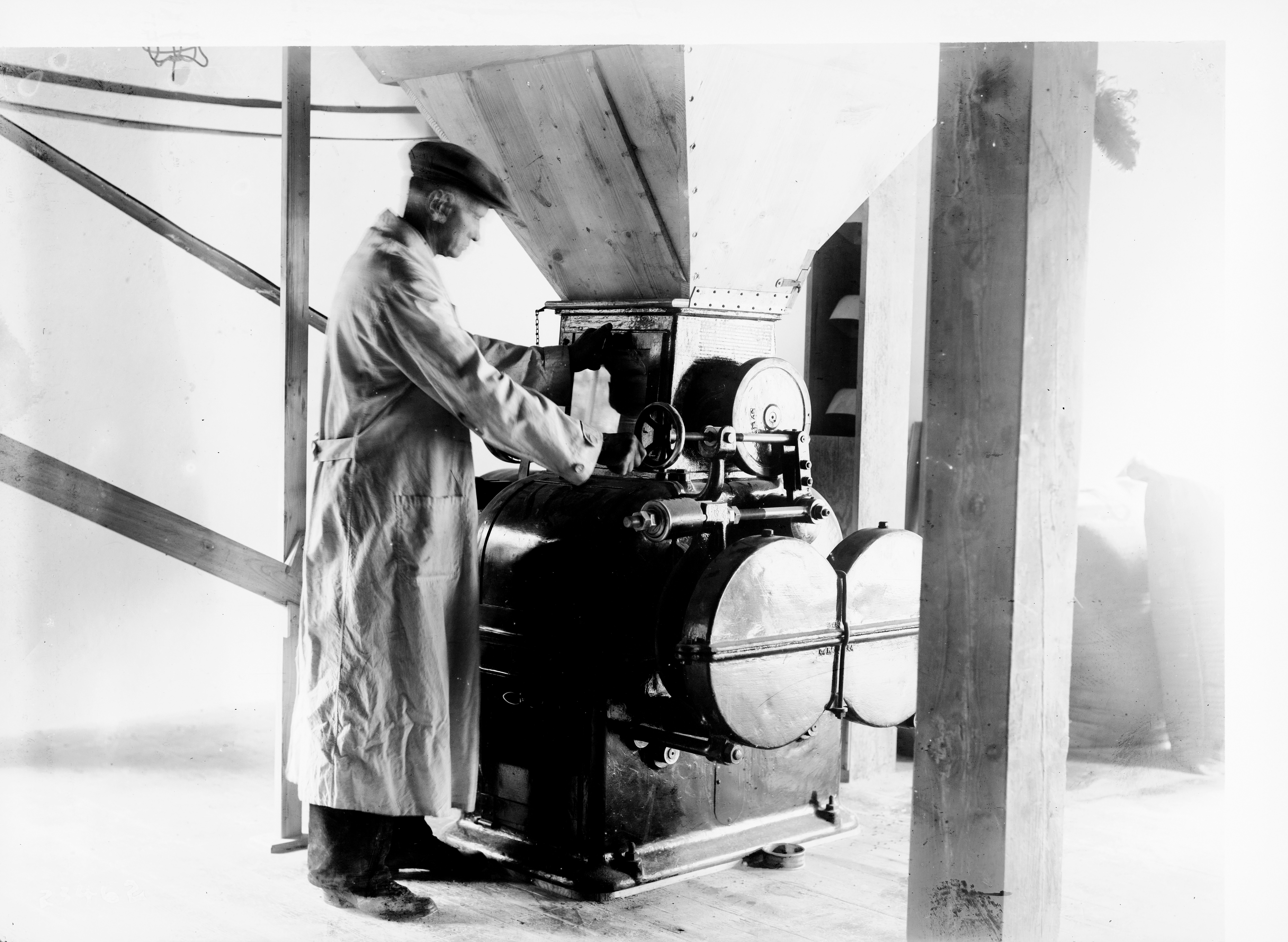 Schwarz-Weiß Foto: Müller an einer Müllereimaschine.