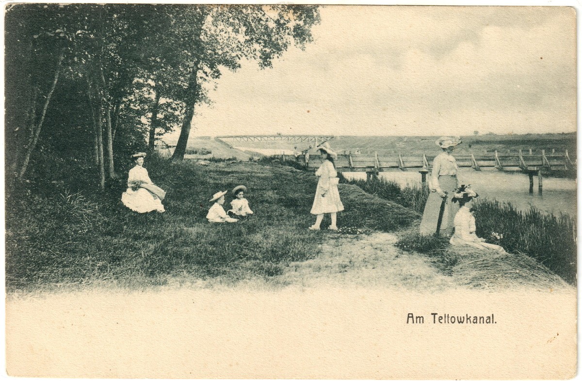 Postkarte mit schwarz-weiß Foto, das vier Frauen und zwei Kinder am Teltowkanal zeigt. Im Hintergrund zwei Brücken.