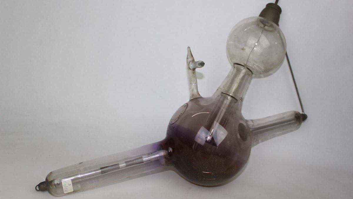 Objekt: Ionen-Röntgenröhre, Die Antikathode ist an einem Draht aufgehängt und als "Tabelette" ausgeprägt. Sie ist von einem Glaszylinder umgeben. Neben der zweiten Kugel über der Antikathode weist die Röntgenröhre auch eine Regenierung auf.